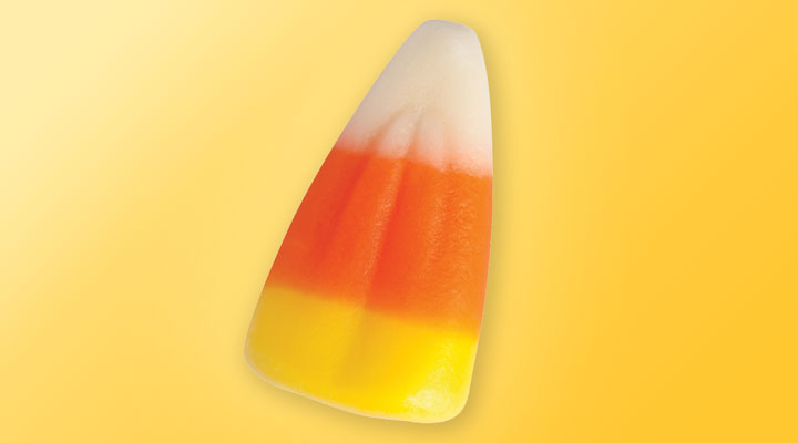 A piece of candy corn on a yellow background