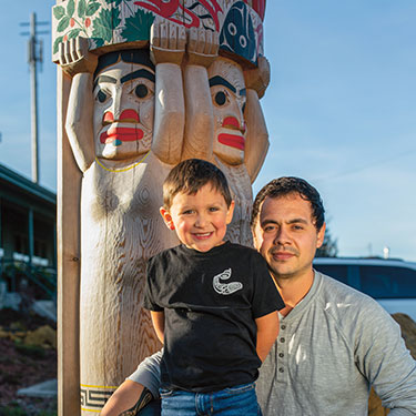 Tain and his father Clifton smile near a totem pole