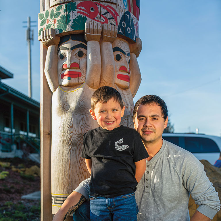 Tain and his father Clifton smile near a totem pole