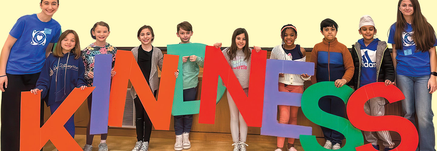 a group of students hold up letters that spell KINDNESS