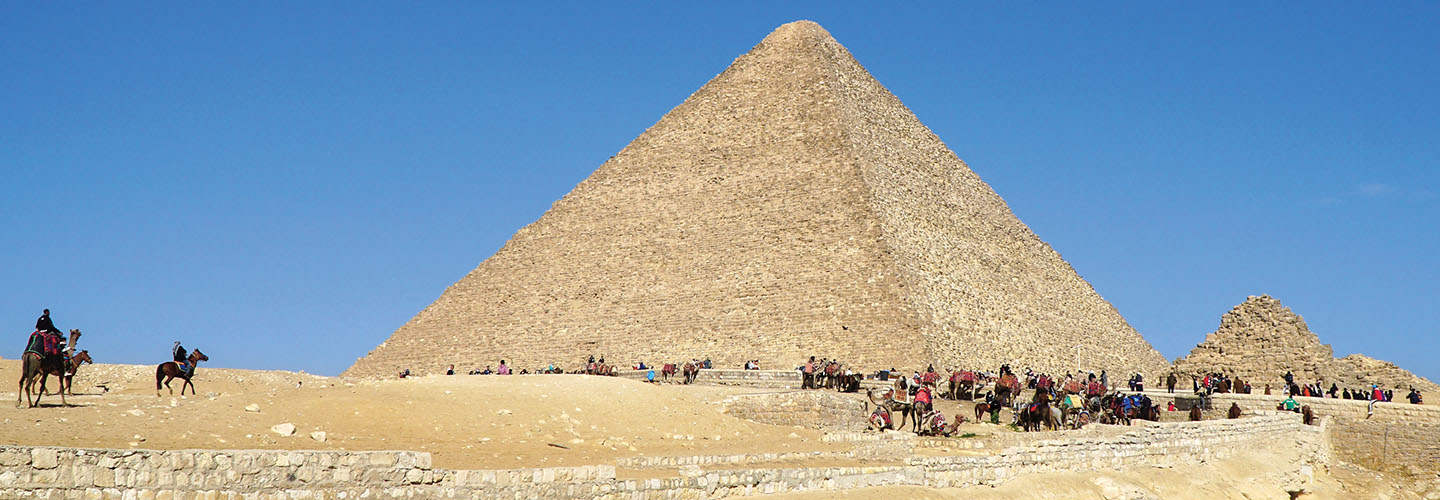 The Great Pyramid of Giza with camels, horses, and people gathered at its base